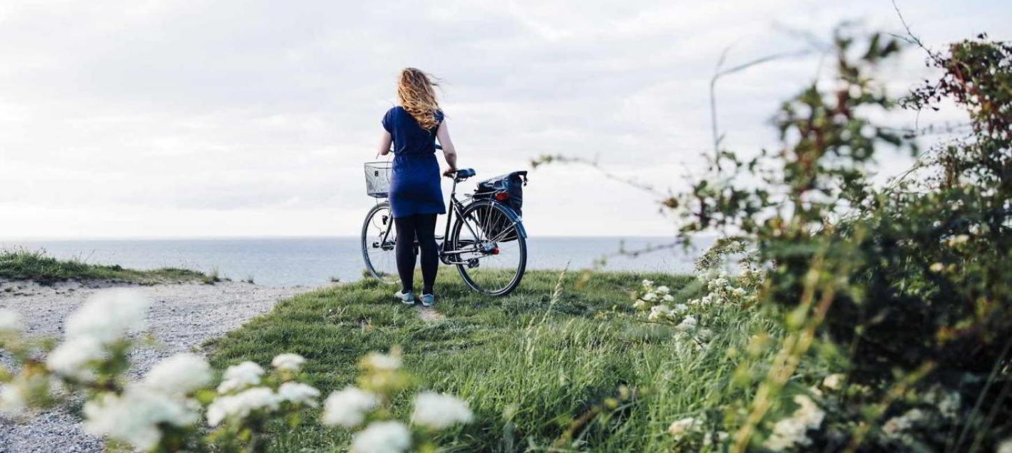 Dame på ved cykel tæt på vandet på Kroneruten