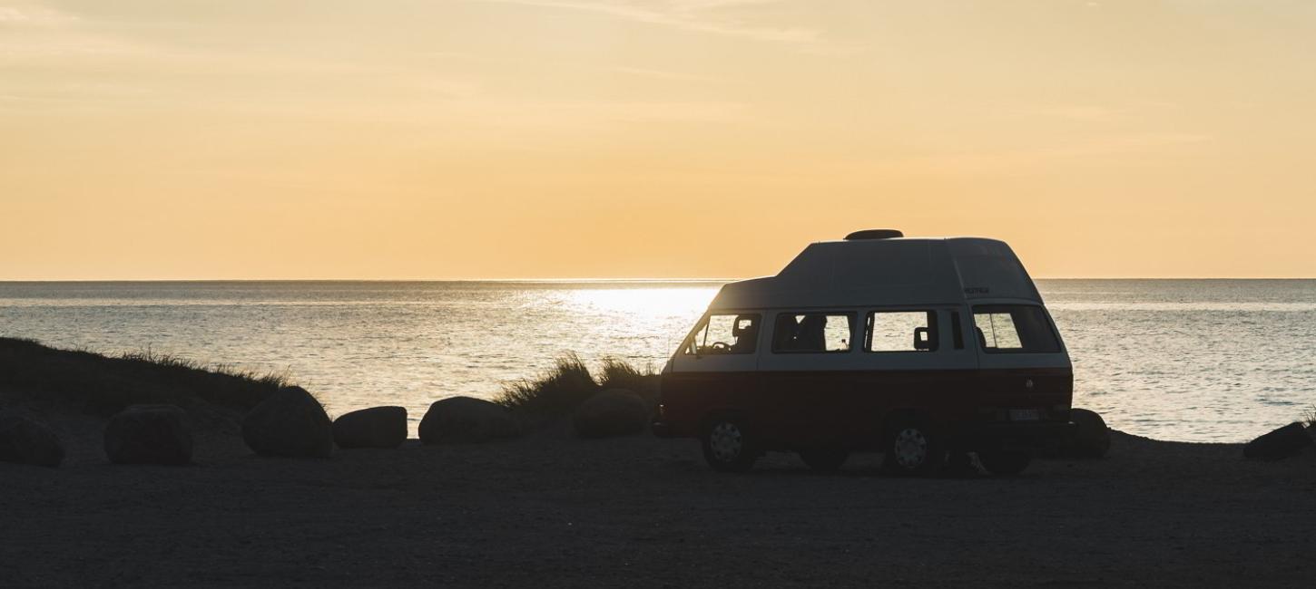 A van parked at the beach edge with the evening sun shining on the sea in North Zealand