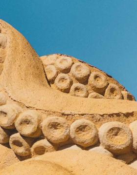 A squid in sand stretches its tentacles towards the sky in Hundested Sand Sculpture Park.